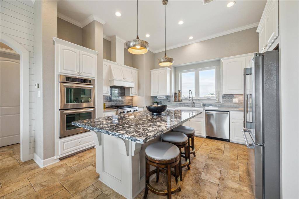 A gourmet kitchen anchors the space, complete with a generous island, high-end appliances, and a walk-in pantry, making entertaining effortless.