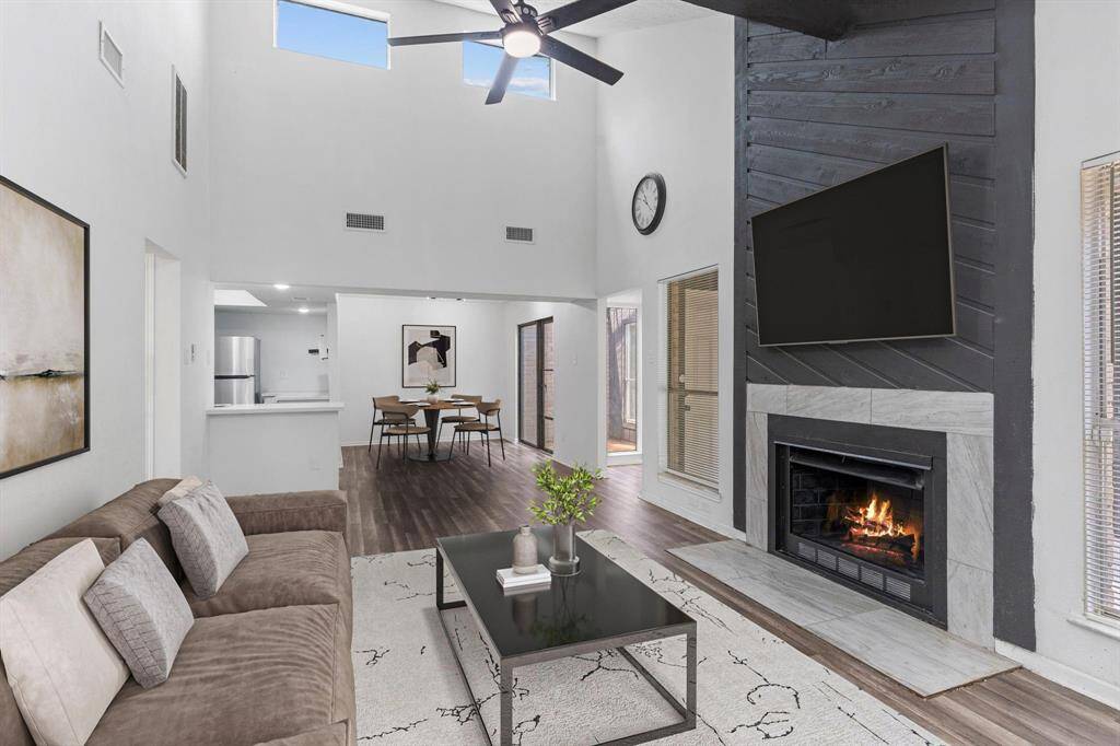 Dramatic huge family area with high vaulted ceilings, wooden beam, ceiling fan, walls of windows and more! Ready for your memories today! Enjoy the warmth of the central living area, showcasing a dramatic floor-to-ceiling fireplace, vaulted ceiling, and open sightlines to the kitchen and atrium.