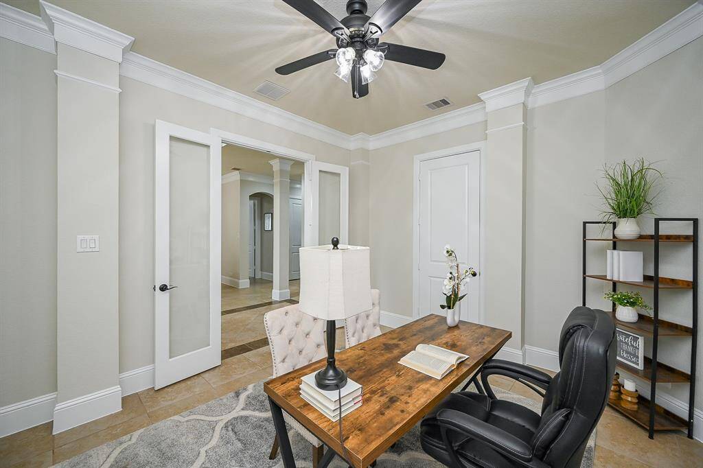 The home office with elegant French doors, a ceiling fan, and neutral color tones. A cozy and functional workspace.