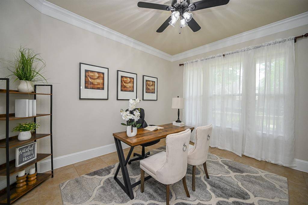 A bright, inviting home office with a large window featuring sheer curtains. Acomfortable and productive workspace.