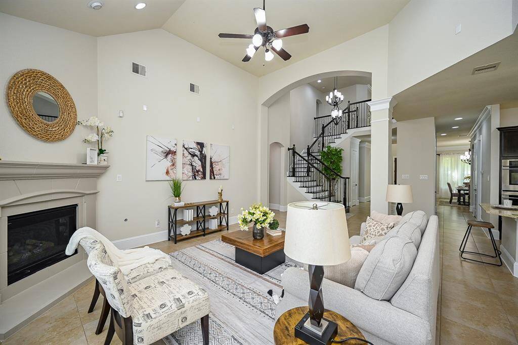This spacious living room opens to a modern kitchen and dining area, with a grand staircase adding a touch of sophistication.