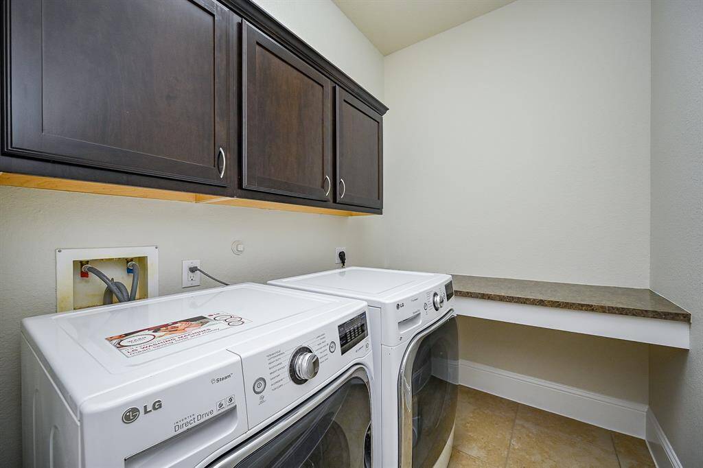 The laundry room features washer and dryer hook ups, dark wood cabinets for ample storage, and a spacious countertop for folding clothes.