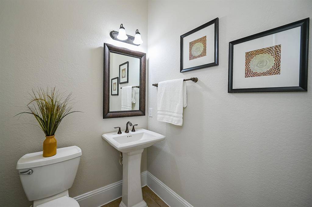A compact, well-lit powder bath featuring a pedestal sink.
