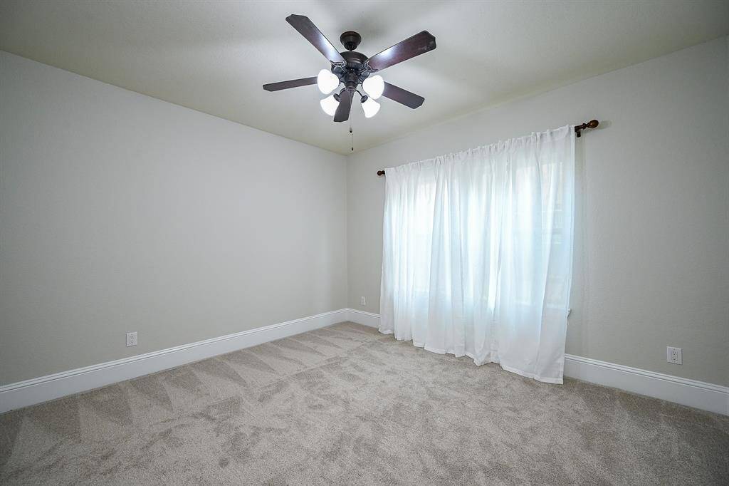 This secondary room features a large window with sheer curtains letting in natural light, creating a bright and airy space.