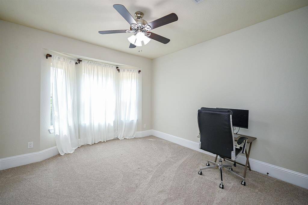Bright and spacious secondary room with soft carpet, a ceiling fan, and large windows with sheer curtains.