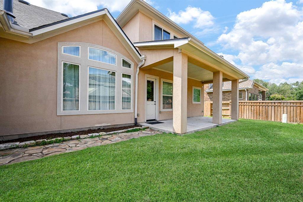This home features a charming backyard with a covered patio, large windows, and well-maintained lawn, perfect for outdoor relaxation.