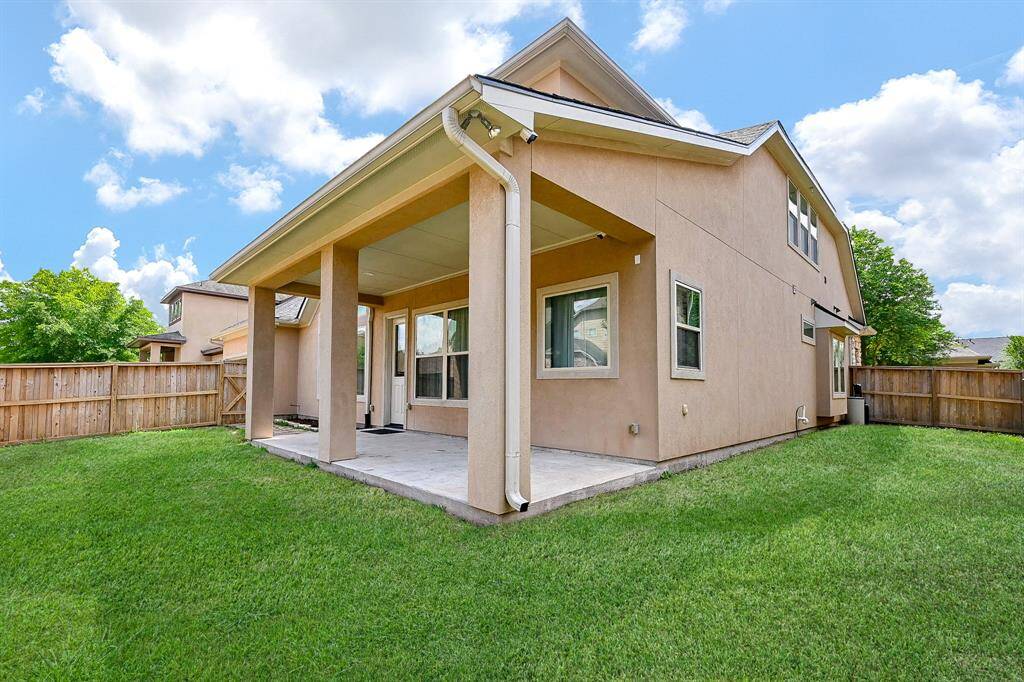 A modern, two-story home with a stucco exterior and a covered back patio. A well-maintained lawn, perfect for outdoor activities.