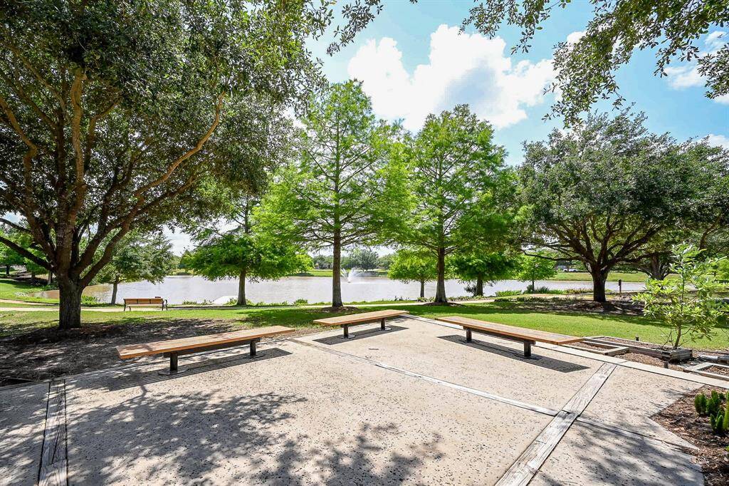 A serene outdoor space with a paved seating area, surrounded by lush trees and overlooking a peaceful pond. Ideal for relaxation and enjoying nature in Telfair.