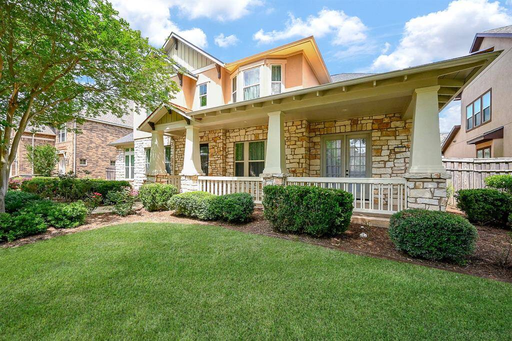 Charming two-story home with a stone facade and inviting front porch. Surrounded by well-maintained landscaping, the house features a spacious yard and cozy outdoor seating area.