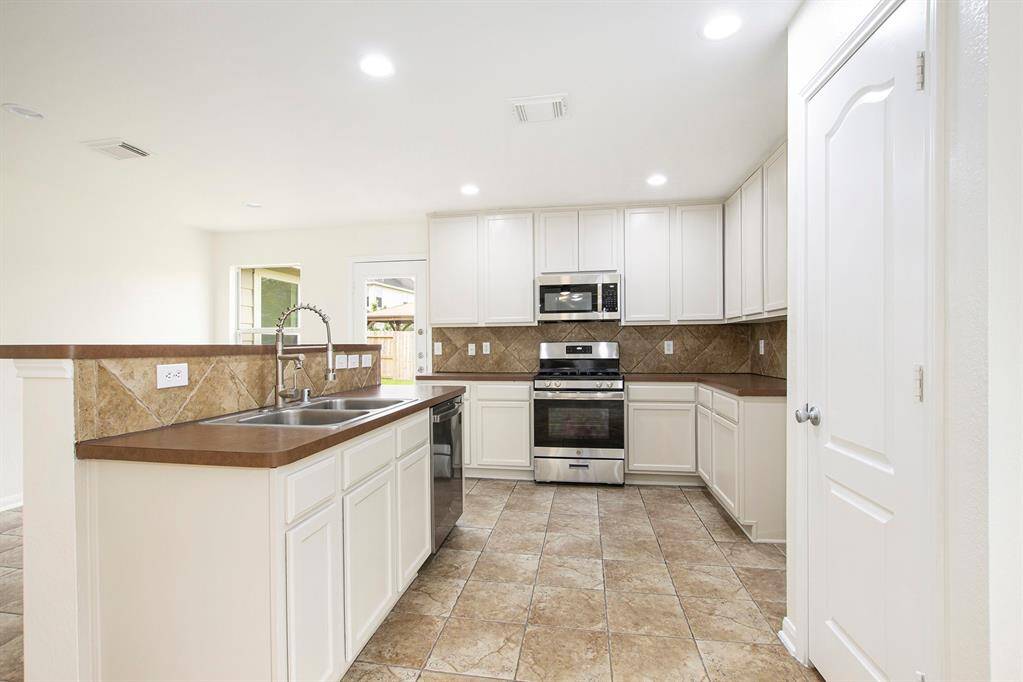 This view captures the kitchen as you walk in, featuring brand-new appliances including a gas range stove, built-in microwave, and dishwasher, along with freshly painted cabinets and a sleek, modern kitchen faucet for added style and functionality.