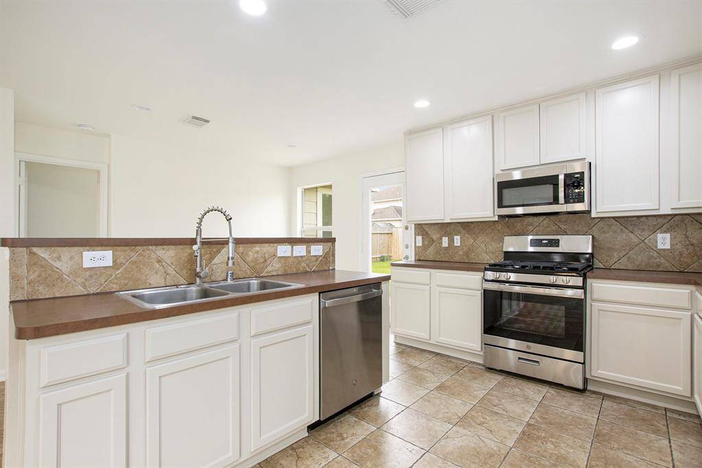 From this angle, the kitchen is beautifully showcased with an additional entry or exit leading to the back door, providing convenient access to the backyard and enhancing the home's flow.