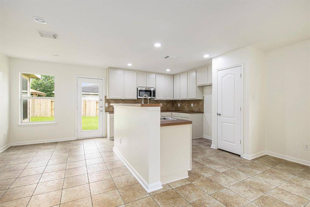 This view highlights the kitchen island, offering space for additional barstools, along with room for a cozy breakfast nook and easy access to the back door, combining practicality with comfort.