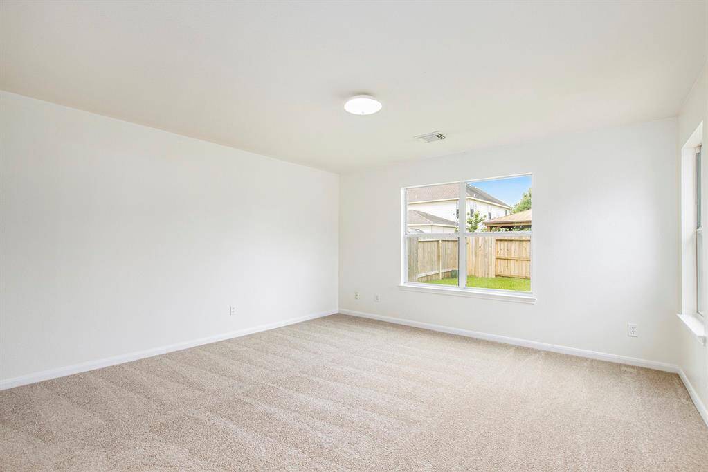 Entering the primary bedroom, you're greeted with beautiful natural lighting, brand-new carpet, and ample space, perfect for fitting a California king bed and creating a serene, spacious retreat.