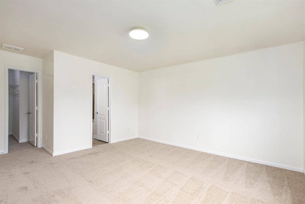 This view highlights the door leading to the walk-in closet, as well as the entry to the private primary bathroom, offering easy access and thoughtful design.
