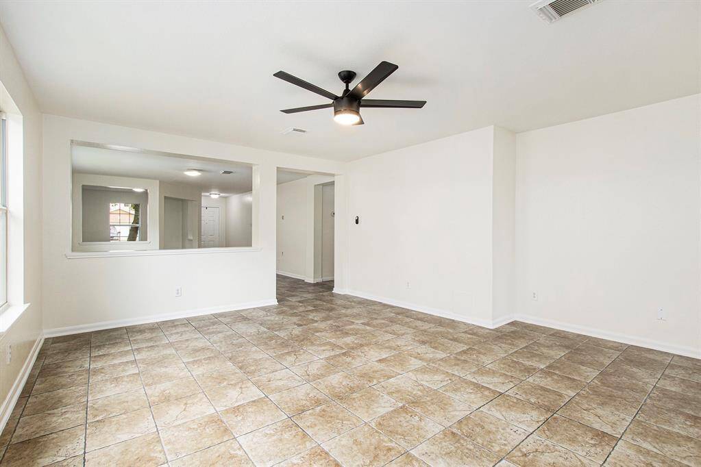This photo takes us from the primary bedroom, back toward the front of the home, leading into the hallway that connects to the mud room/laundry room, with access to the two-car garage, two additional bedrooms, and the second bathroom.