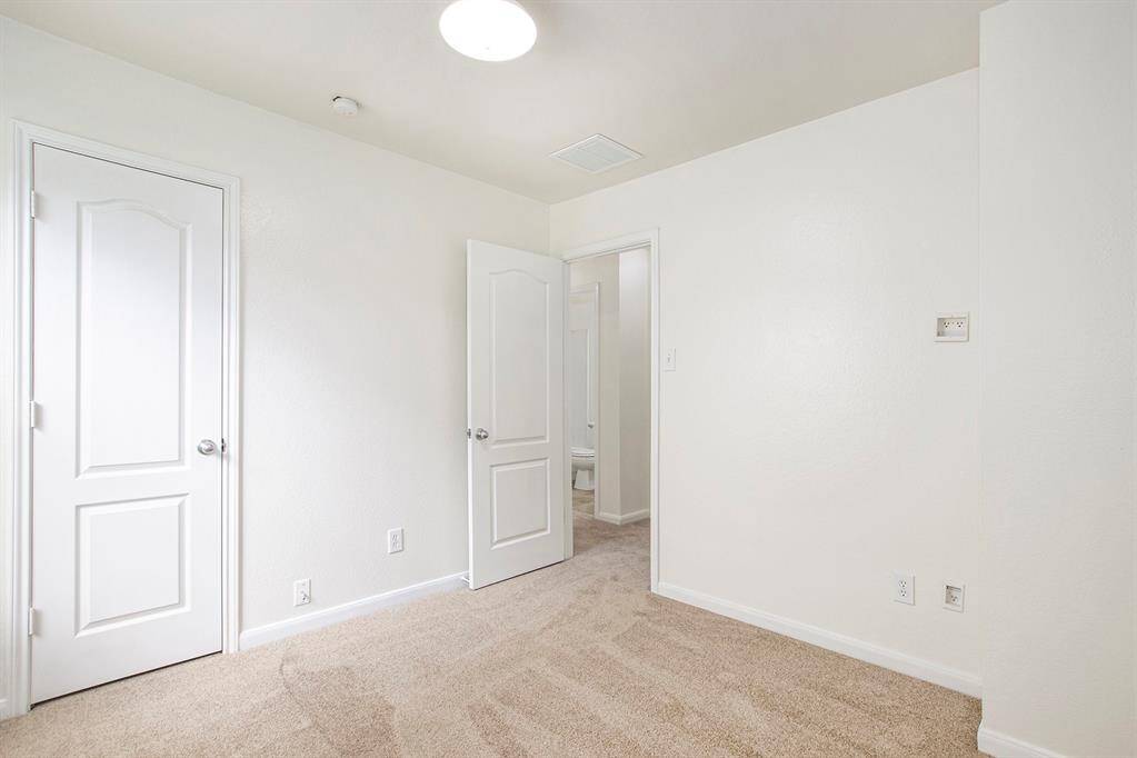 This angle of the first bedroom showcases the closet door and the entryway leading into the hallway, providing a clear view of the room's layout and flow.