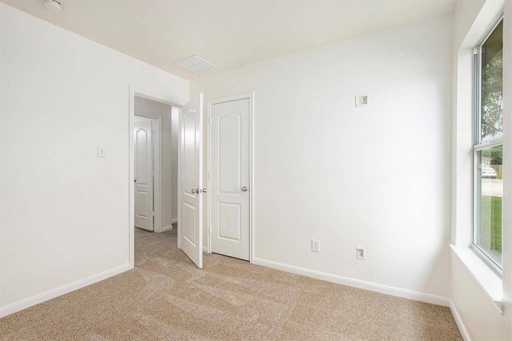 This photo shows a view from the third bedroom, facing the door that leads to the hallway and the second bathroom, offering a clear connection to the home's main living areas.