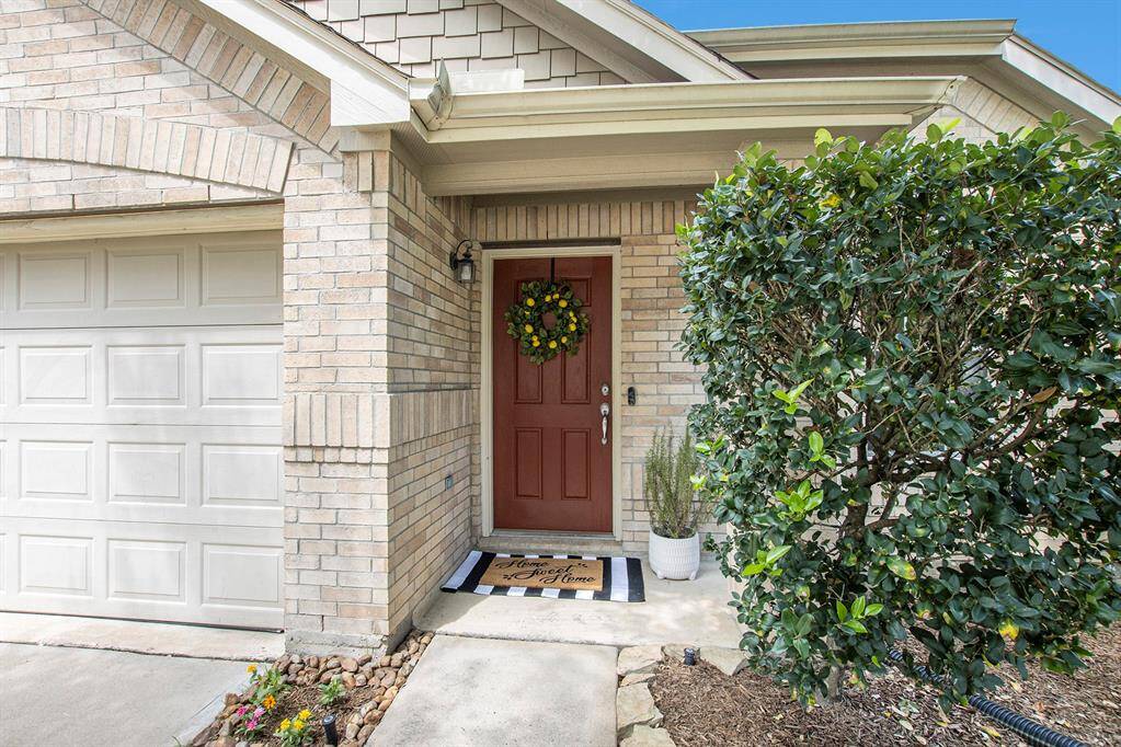 The freshly painted red door and covered entryway create a warm, inviting welcome with a pop of color and added charm.