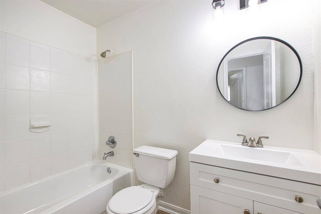 The shared bathroom in the hallway, located conveniently in front of both rooms, features a new vanity, light fixture, and mirror, adding a modern touch to the space.