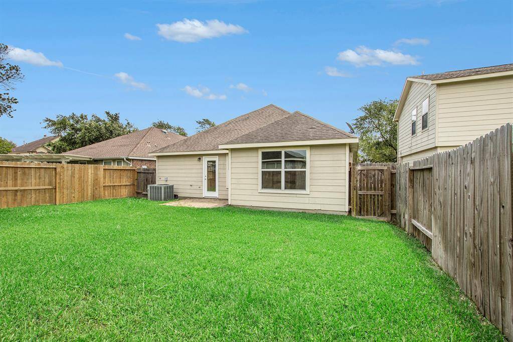 This view captures the back corner of the yard, showcasing the beautiful back of the home and the inviting patio area—a perfect space for outdoor gatherings, quiet evenings, or simply enjoying the tranquility of your own backyard. Come experience the warmth and charm in person, this home is ready to welcome you.