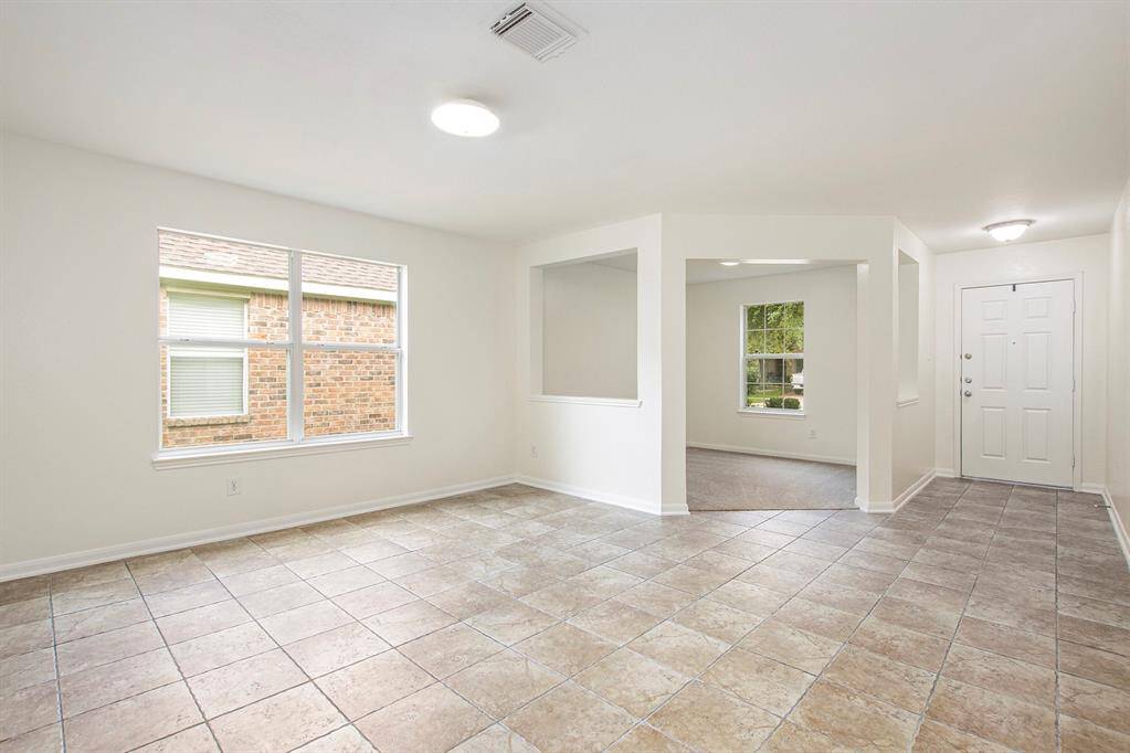 This view, taken from the versatile living or dining area, looks back toward the front door and office entry, highlighting the home's thoughtful layout and inviting flow from the moment you walk in.