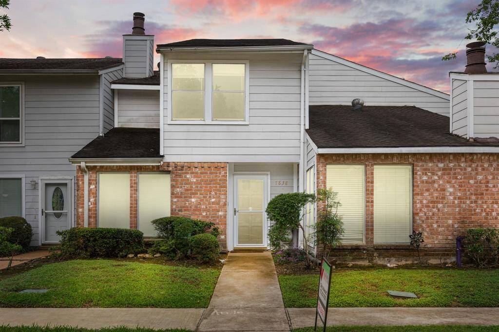 This charming townhouse features a blend of brick and siding exterior with a welcoming front path and well-maintained shrubbery. It offers a cozy, inviting atmosphere, perfect for a small family or first-time homebuyers. The sky adds a beautiful backdrop, enhancing the curb appeal.