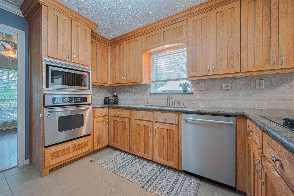 The kitchen features granite countertops, undermount lighting, and stainless appliances.