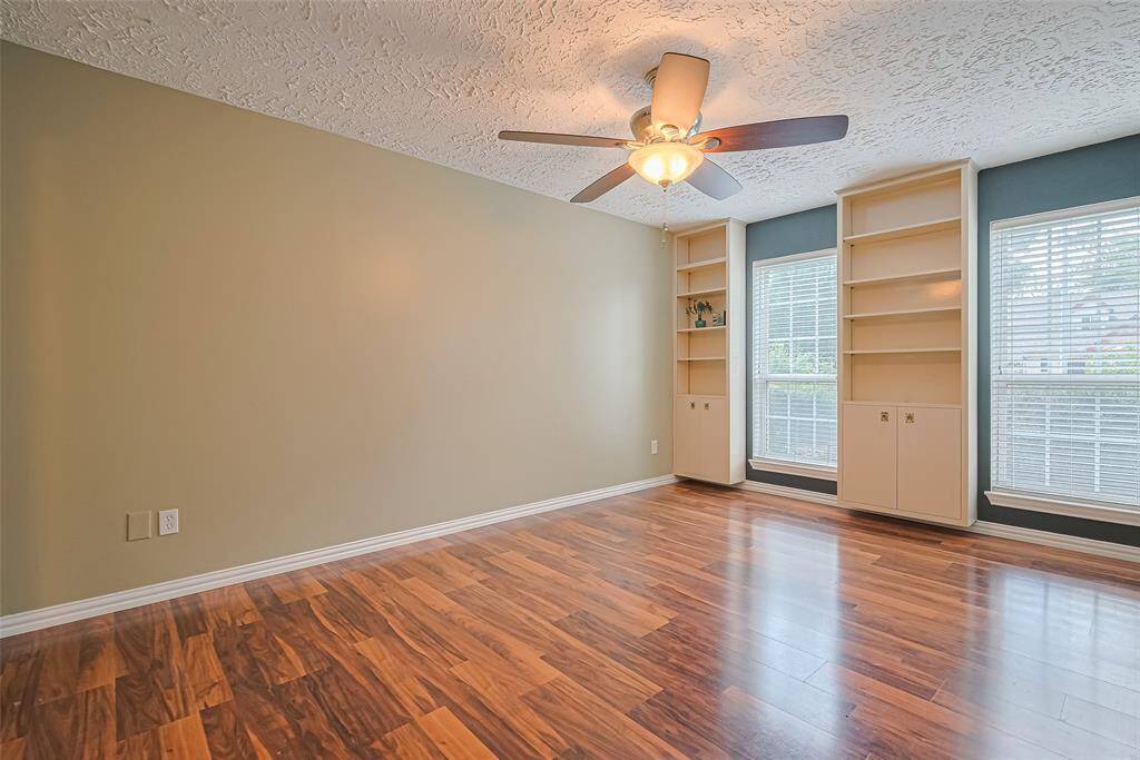 Primary bedroom features rich wood-look laminate flooring, ceiling fan & and fresh paint.