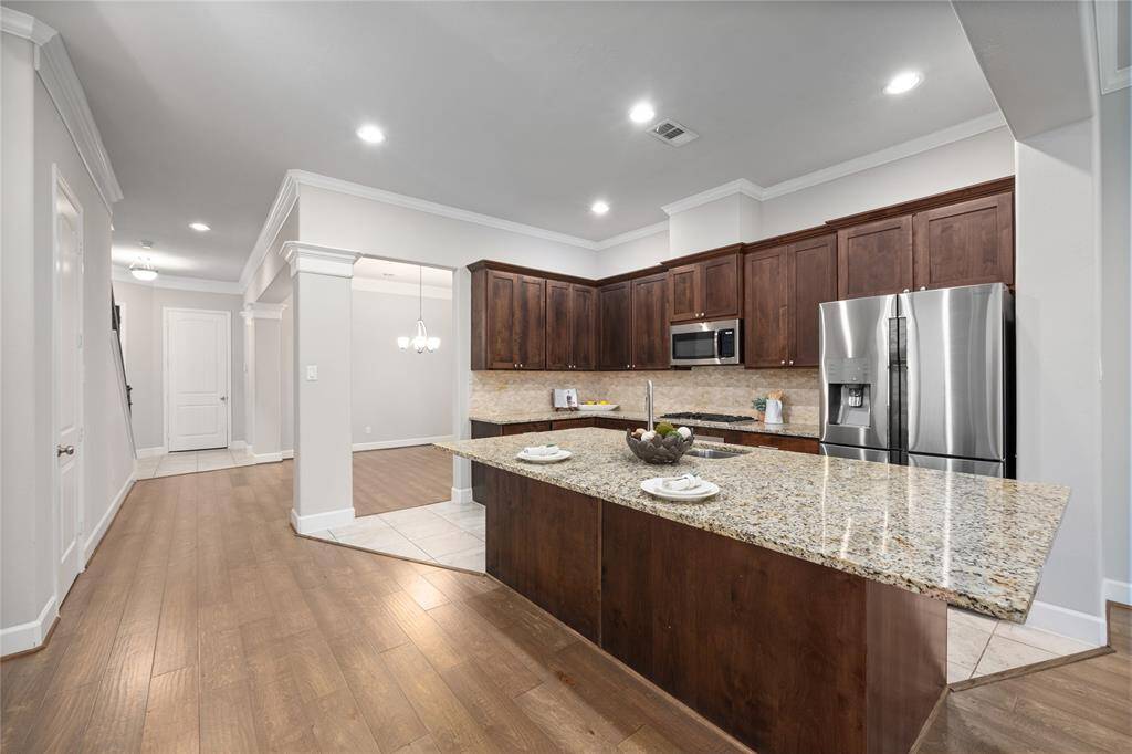 Just past the dining area is this grand, spacious, and functional kitchen...featuring this massive kitchen island, stainless steal appliances, an ample amount of cabinets, and a gas cooktop.