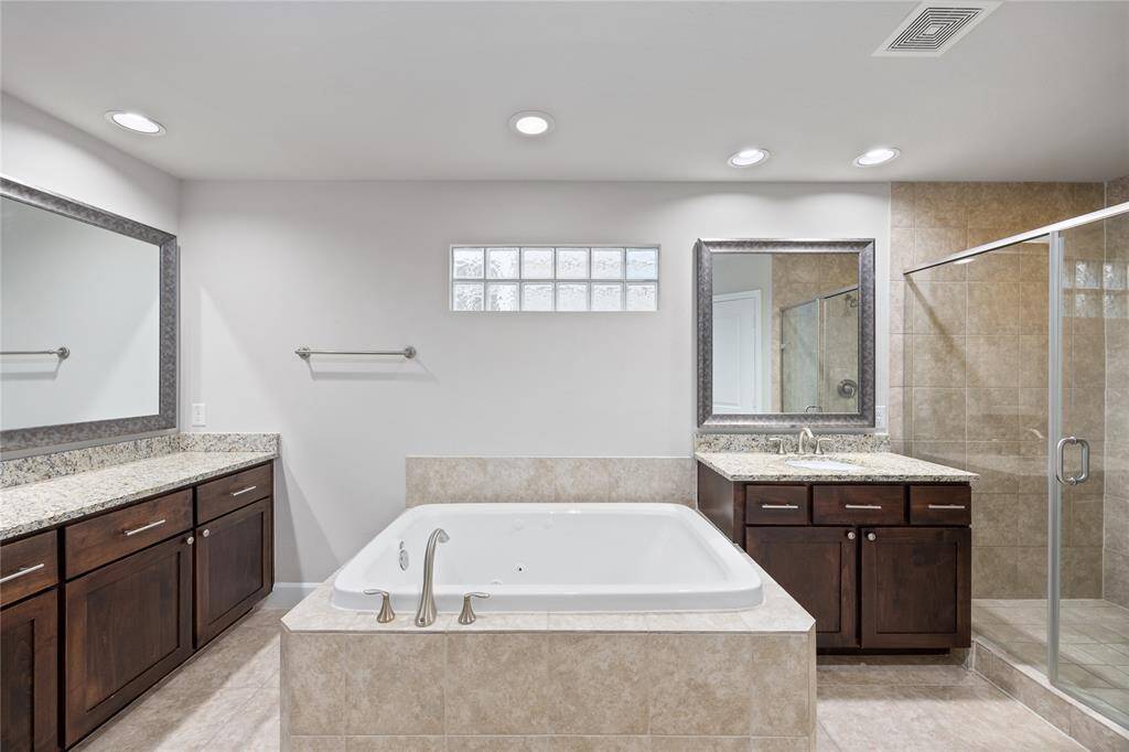 Primary Bathroom featring a separate soaking tub, large walk in shower, and two separate vanity areas!