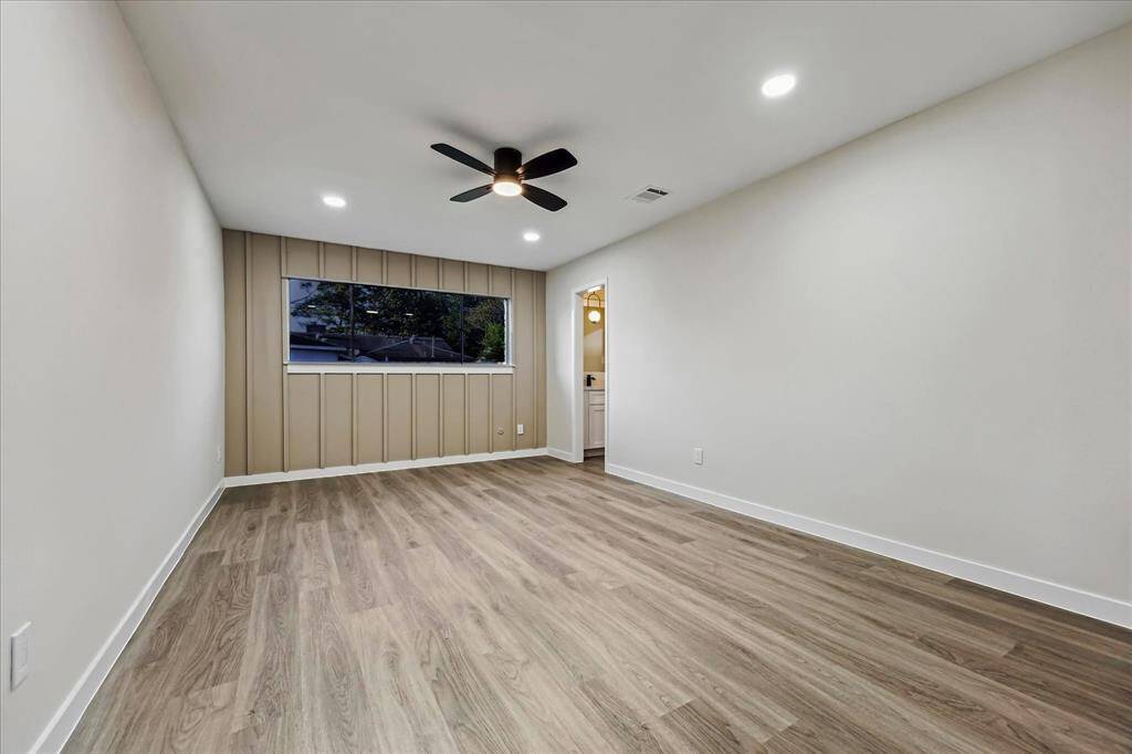 Primary Bedroom w/ accent wall paneling, recessed lighting, and ensuite bath access