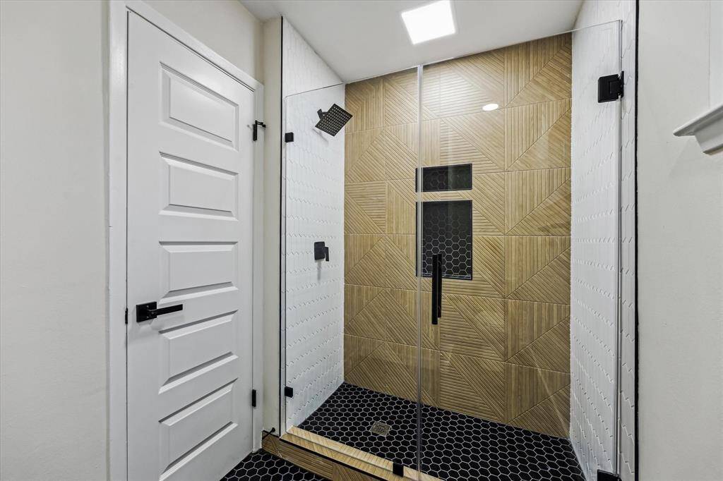 Custom Walk In with geometric wood-look tile, frameless glass, and matte finished