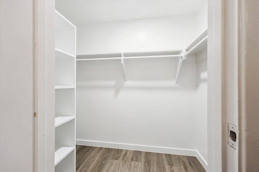 Primary spacious walk in closet with built in shelving.