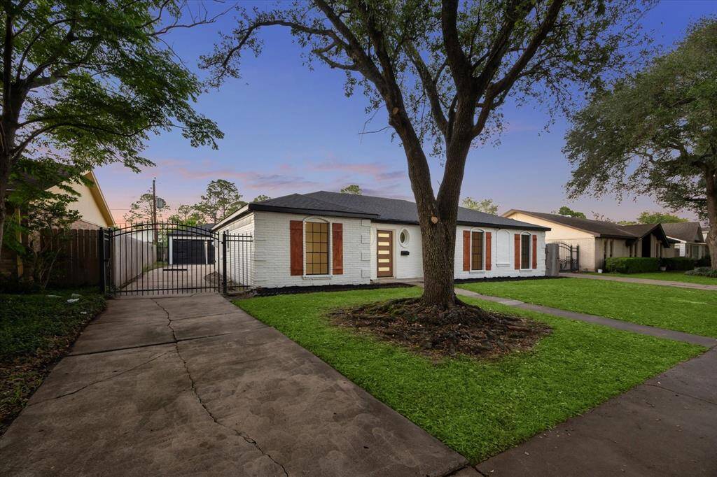 Extended Driveway with Wrought Iron gate leads to a detached garage. Custom Cedar Shutters
