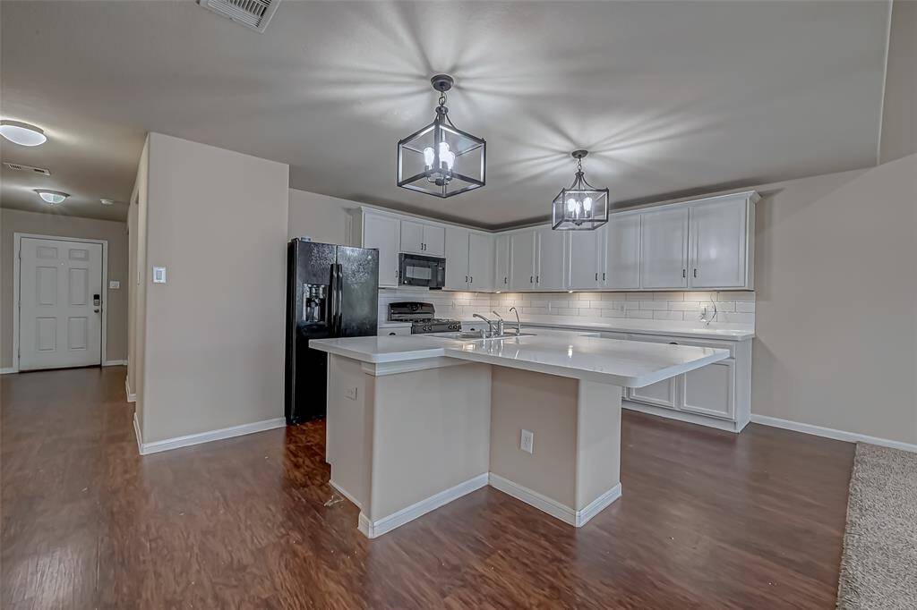 The kitchen features pristine white countertops that create a bright, clean workspace, beautifully complemented by a generous breakfast bar. Ideal for casual family meals or entertaining guests, this expansive bar adds both style and function to the heart of the home.