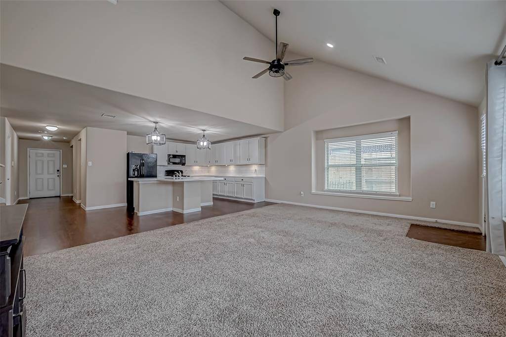 The living room boasts soaring high ceilings, creating an airy, expansive atmosphere that enhances the sense of space. This architectural feature adds a dramatic touch, making the room feel both open and inviting, perfect for family moments or entertaining guests.