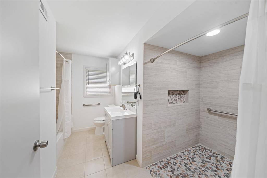 Remodeled bath that is handicap accessible with a large roll in shower, and additional shower tub combo.