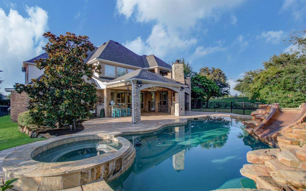 This beautiful home features a spacious backyard with a luxurious pool and hot tub, complemented by a stone patio and covered outdoor area perfect for entertaining.