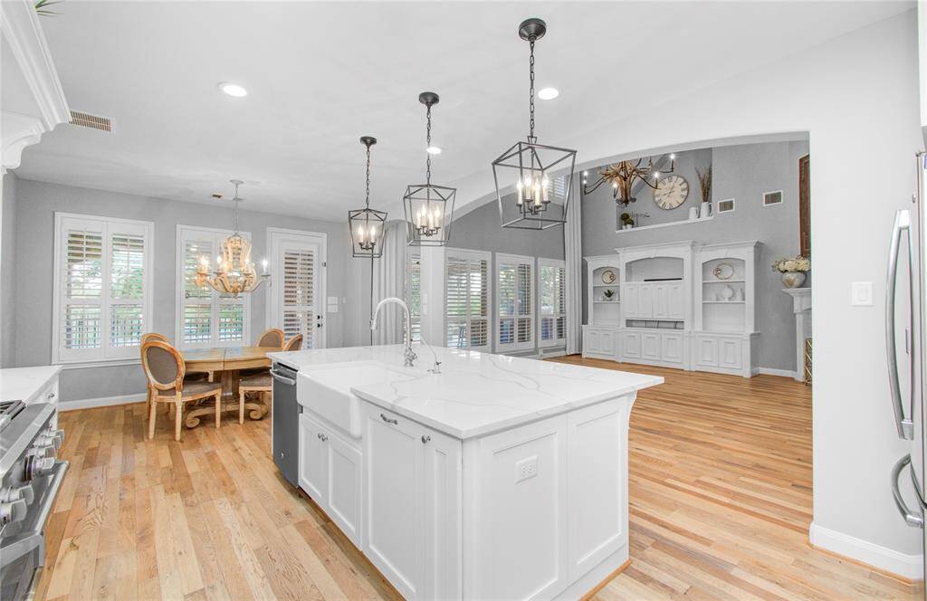 Bright, open kitchen and breakfast area, a central island, and elegant pendant lighting. Features include white all wood custom Kent Moore cabinetry, stainless steel appliances.