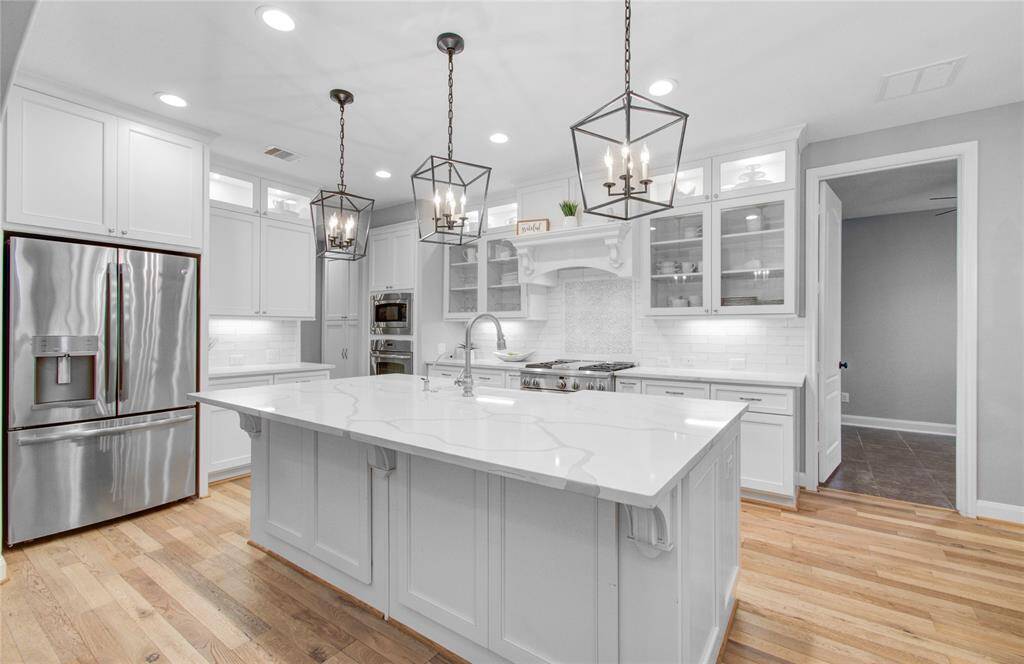Elegant pendant lighting above the oversized island quartz with plenty of storage below perfect for entertaining and storing the family games.