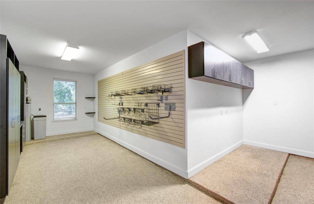 A mans dream- spacious 3-car garage with built-in cabinets, wall storage, and ample overhead space—ideal for organized living. The floor features a durable epoxy coating.