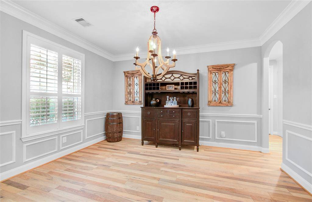 Bright dining room featuring hardwood floors, and a large window with shutters. A stylish dimmable chandelier hangs lovely over any dinner table.