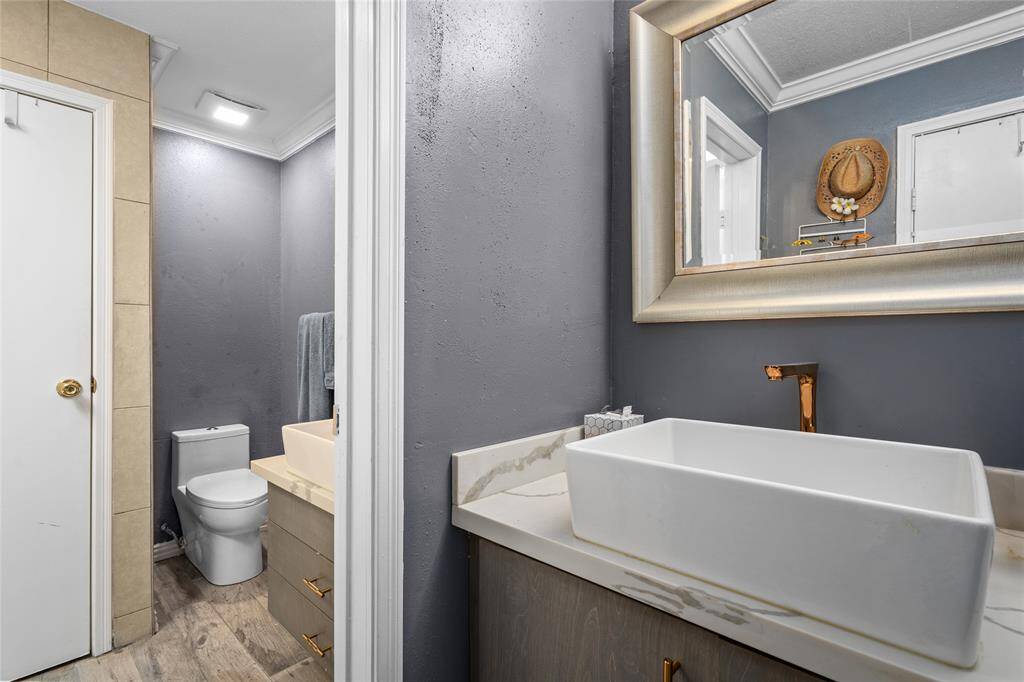 This stylish secondary bathroom features a contemporary vanity with a sleek countertop and a modern vessel sink. The two-part layout provides added functionality, separating the vanity area from the toilet and shower space. A neutral color scheme and elegant finishes enhance the overall aesthetic, creating a refined and inviting atmosphere.