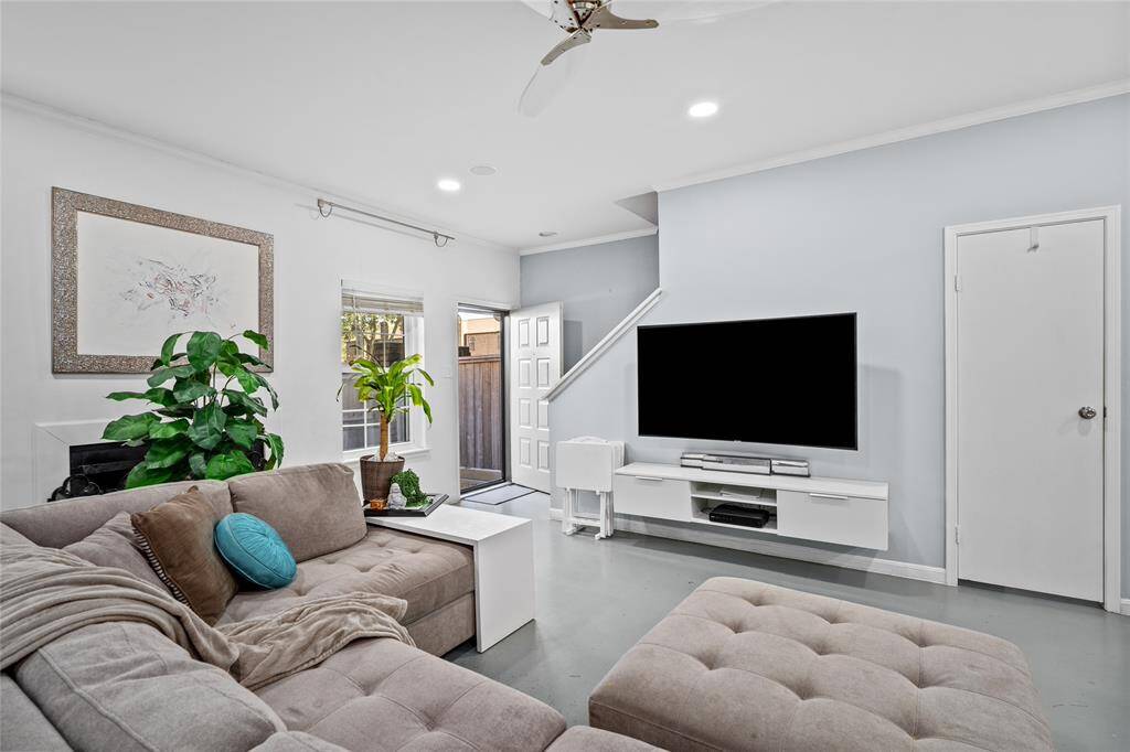 This inviting living room offers a spacious, open-concept design with modern finishes and a neutral color palette. Natural light streams in through the large window, creating a warm and welcoming atmosphere. The front door provides easy access, while the nearby staircase leads to the upper level. Recessed lighting and a sleek ceiling fan enhance the contemporary feel. A conveniently located half-bathroom is tucked away for guests, adding to the functionality of the space.