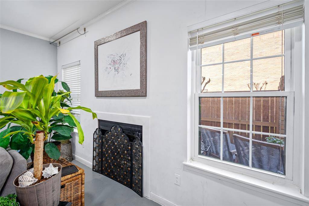 This inviting corner of the townhome features a charming fireplace framed by a decorative screen, adding warmth and character to the space. A large window allows for plenty of natural light and offers a view of the private patio, creating a bright and airy atmosphere. The neutral tones and clean design make this the perfect spot to relax and unwind.