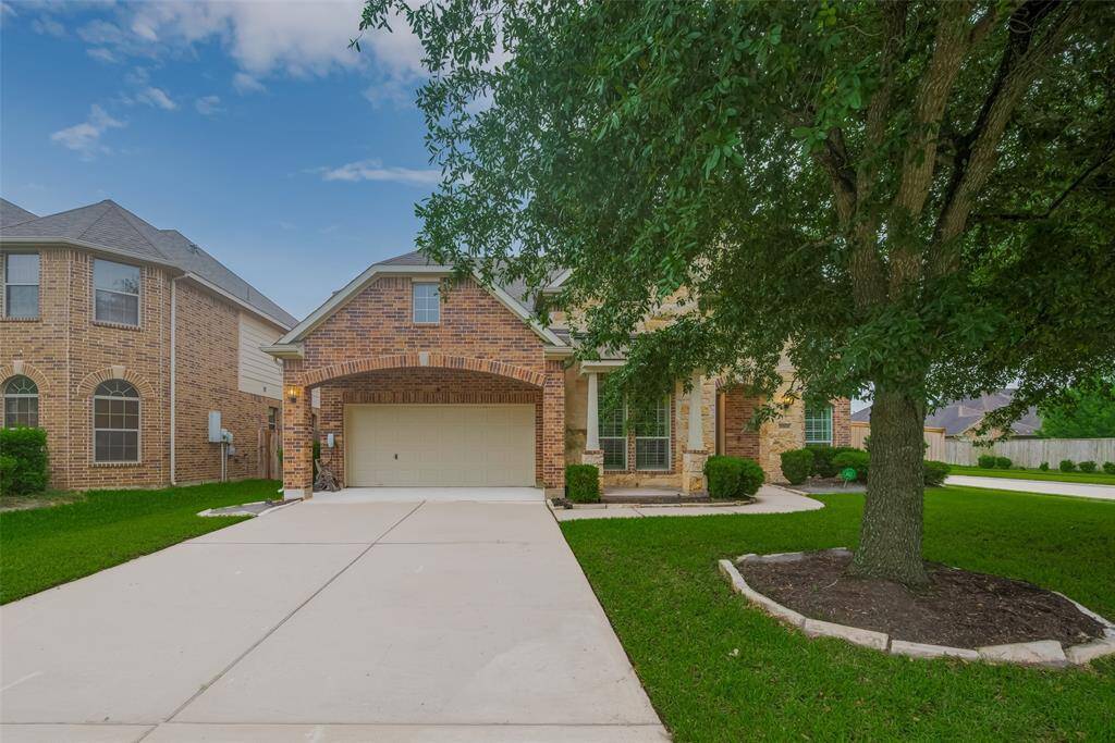 Charming brick home with inviting curb appeal, featuring a spacious driveway and lush landscaping.