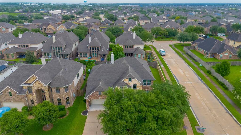 This aerial photo showcases a suburban neighborhood with spacious, well-maintained brick homes. The area features tree-lined streets and neatly manicured lawns, creating a welcoming and peaceful residential setting.