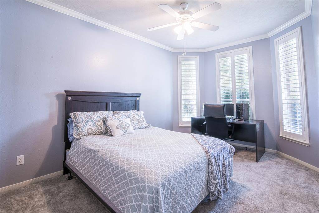 Bedroom 2 is located downstairs at the front of the home. It has a bay window with plantation shutters, crown molding and a ceiling fan. It is connected to an ensuite bathroom.