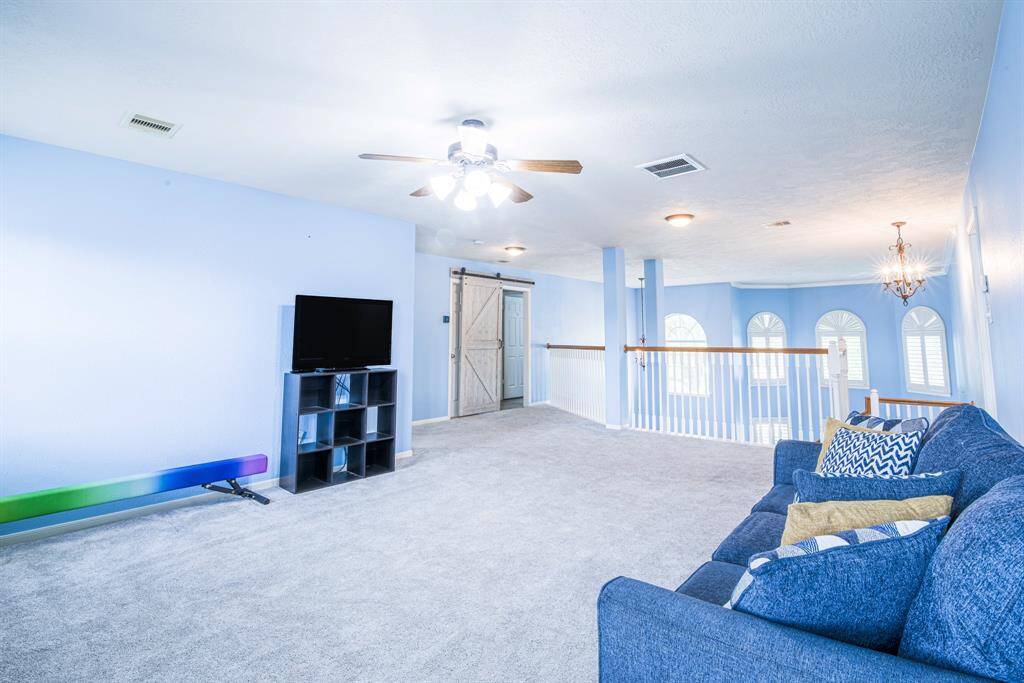 At the top of the stairs sits a large game room with ceiling fan. There is room to even do gymnastics up here! Two suites of rooms are split on each side of the game room.