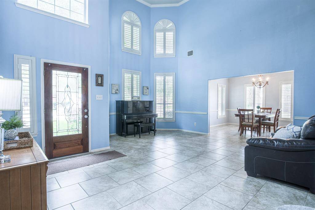 The living room is adjacent to the formal dining room. Notice the wall of windows, each with custom-built plantation shutters.
